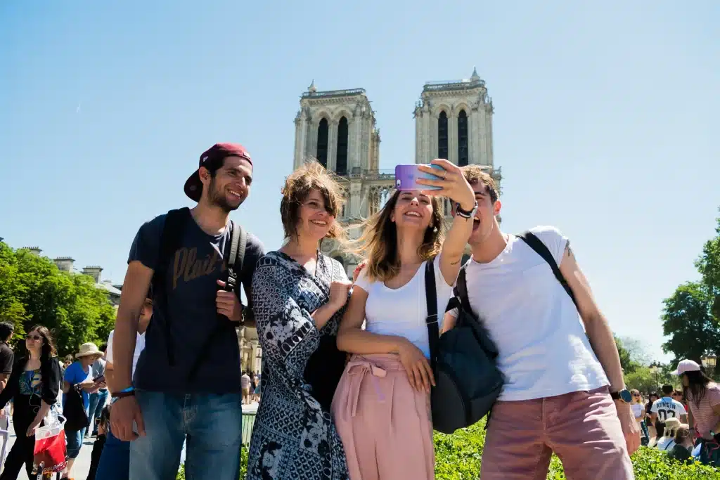 group of people taking a selfie together while standing in front of a historical sight in paris