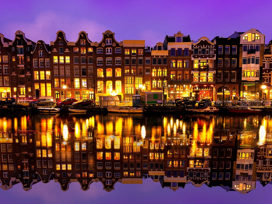 best cities for new year, amsterdam houses at night by the canal
