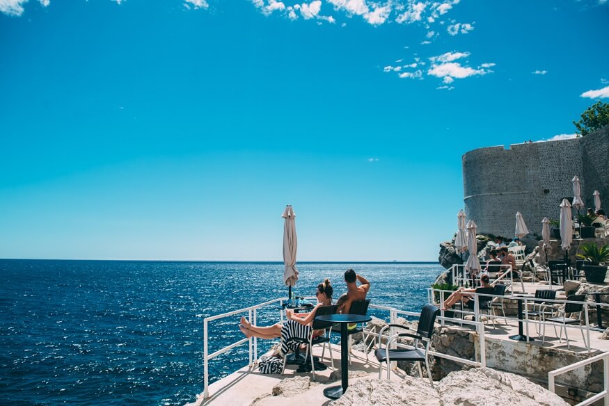 Couple relaxing on a cliff by the ocean in Dubrovnik (c) Lola Wright