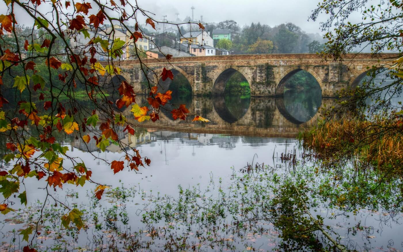 autumnal view of a Roman bridge over the Miño River in Lugo, Galicia