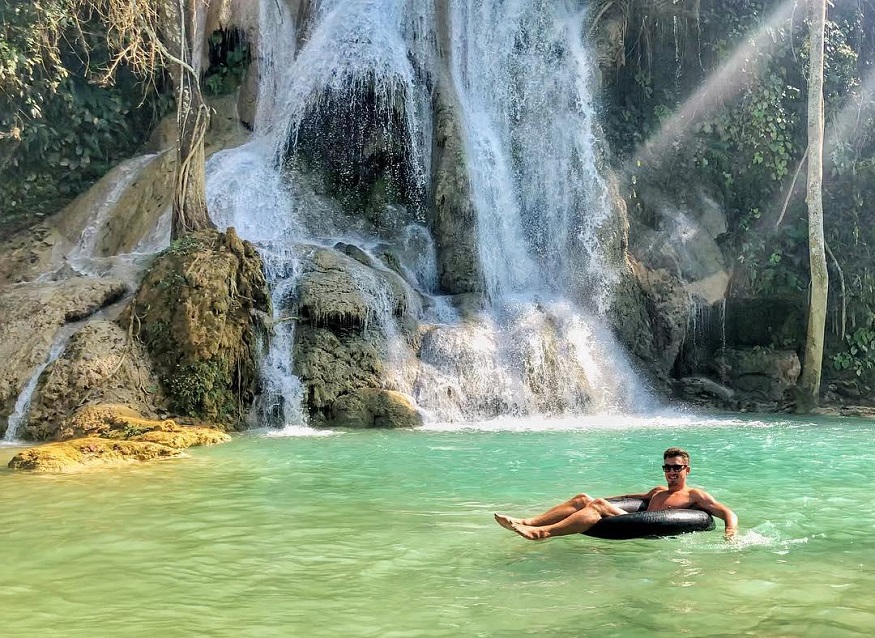 backpacking Laos - man in tube floating near waterfall