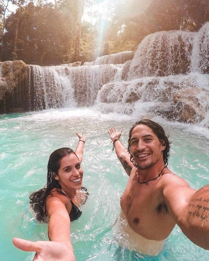 backpacking Laos - man and woman in water by waterfall