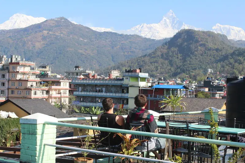 nepal trekking - zwei junge Männer sitzen auf einer Bank und blicken auf die Landschaft von Nepal