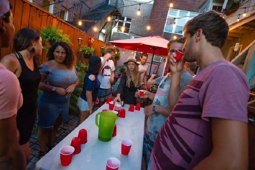 where to stay in new orleans, people playing beer pong at auberge hostel