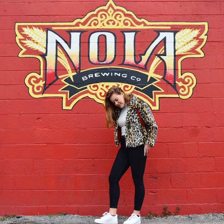 where to stay in new orleans, girl standing in front of nola brewing co painted wall