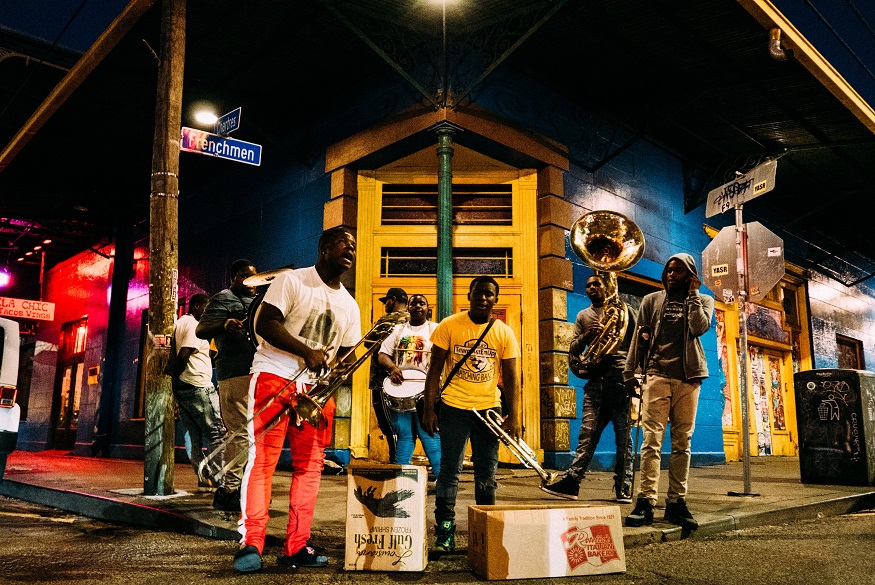 where to stay in new orleans, musicians playing in the street at night with trumpets