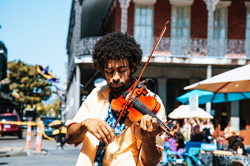 where to stay in new orleans, man playing a violin in the street