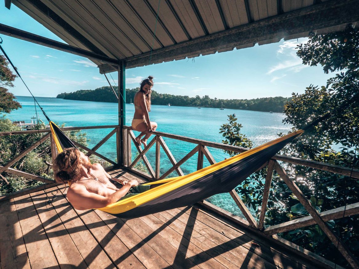 insel sumatra - Junger Mann liegt auf einer gelben Hängematte und blickt aufs türkisblaue Meer hinaus