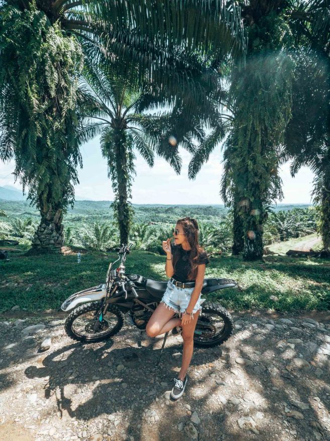 insel sumatra - Ein Mädchen steht vor einem Motorroller inmitten der Natur