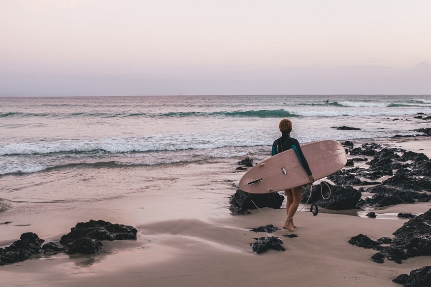 travel east coast australia, person on the beach at byron bay with a surfboard