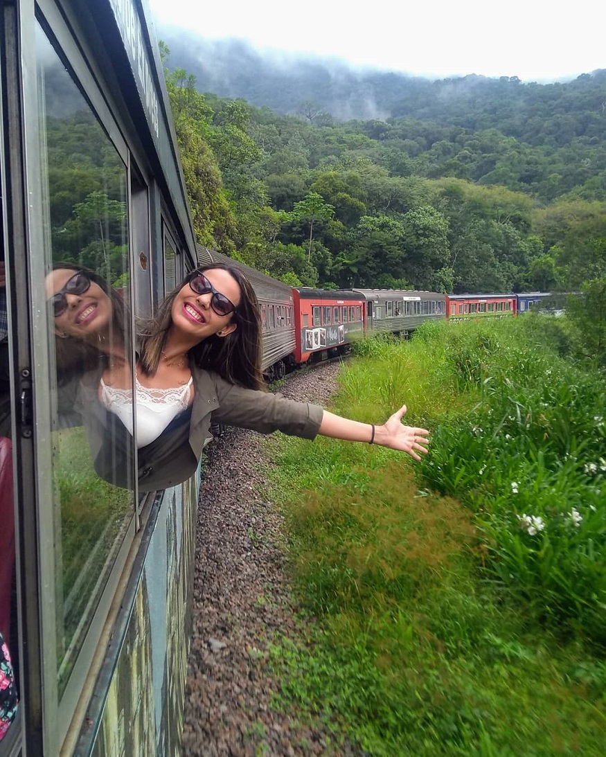 best train journeys, girl hanging out of window on the Serra Verde Express in Brazil