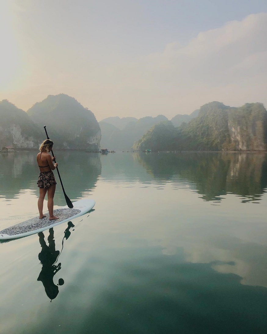 best romantic destinations for solo travellers, girl stand up paddle boarding in halong bay, vietnam