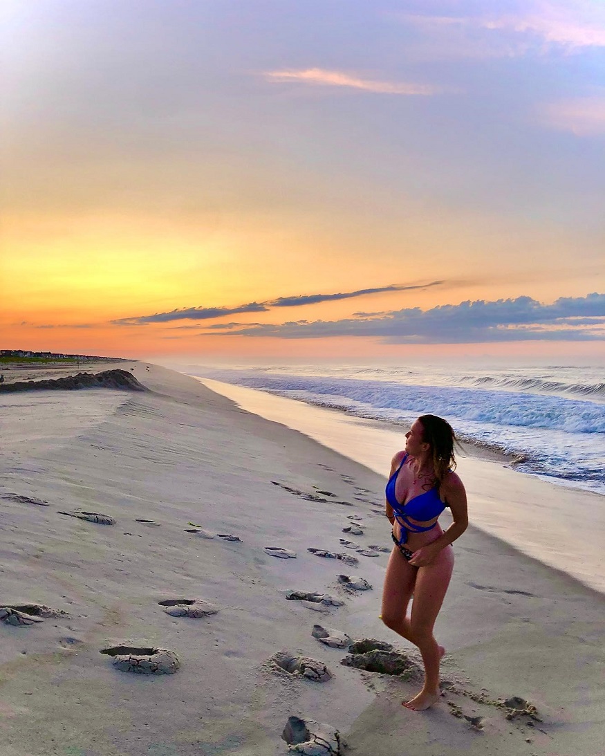 best romantic destinations for solo travellers, girl standing on beach at sunset in the The Hamptons