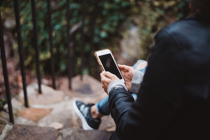 how to cure wanderlust, person sitting on steps with a phone
