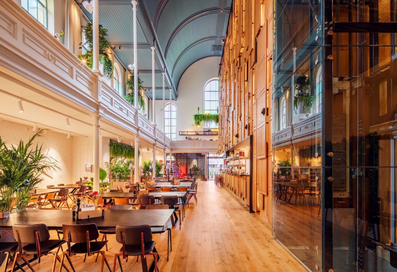 seating area with tables and chairs in an old church at BUNK Utrecht hostel, Netherlands - nominated for extraordinary innovation hostels award