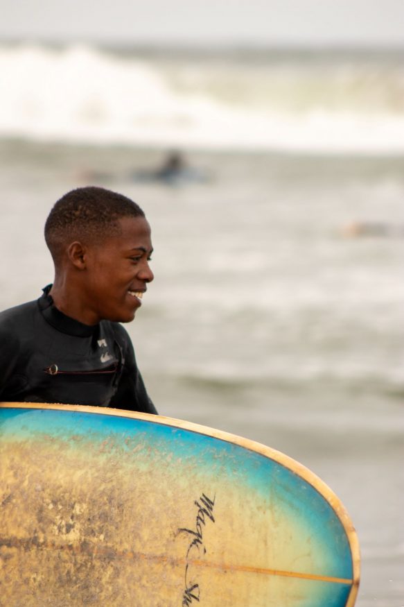 Man with surfboard by Salty Jackal Backpackers & Surf Camp, Namibia - nominated for nominated for extraordinary sustainable hostels