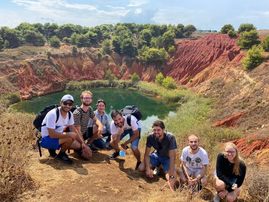 group of people taking a picture on top of a hill they hiked
