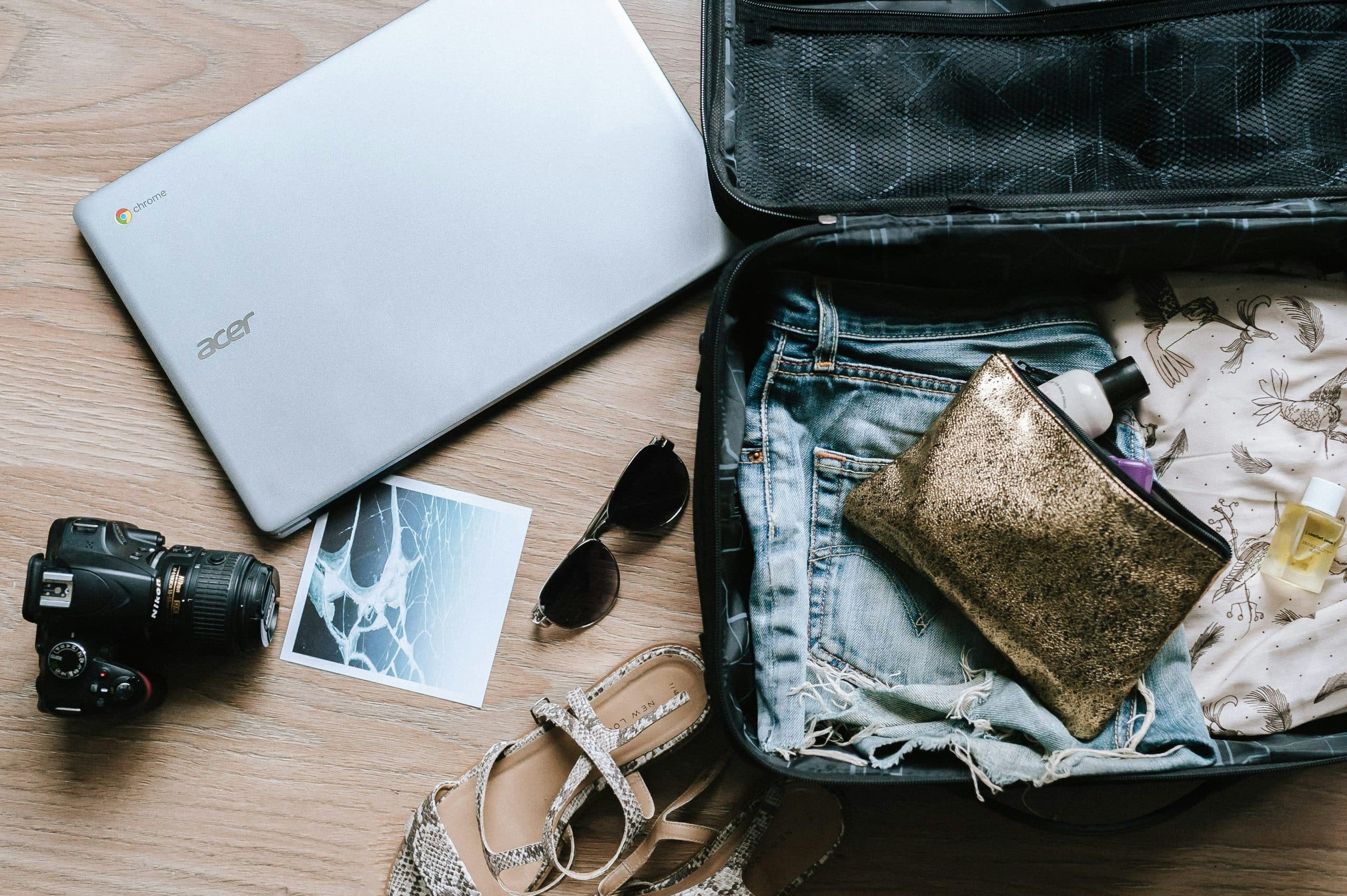 Image showing open suitcase during the packing process, with clothes, a laptop, shoes and more