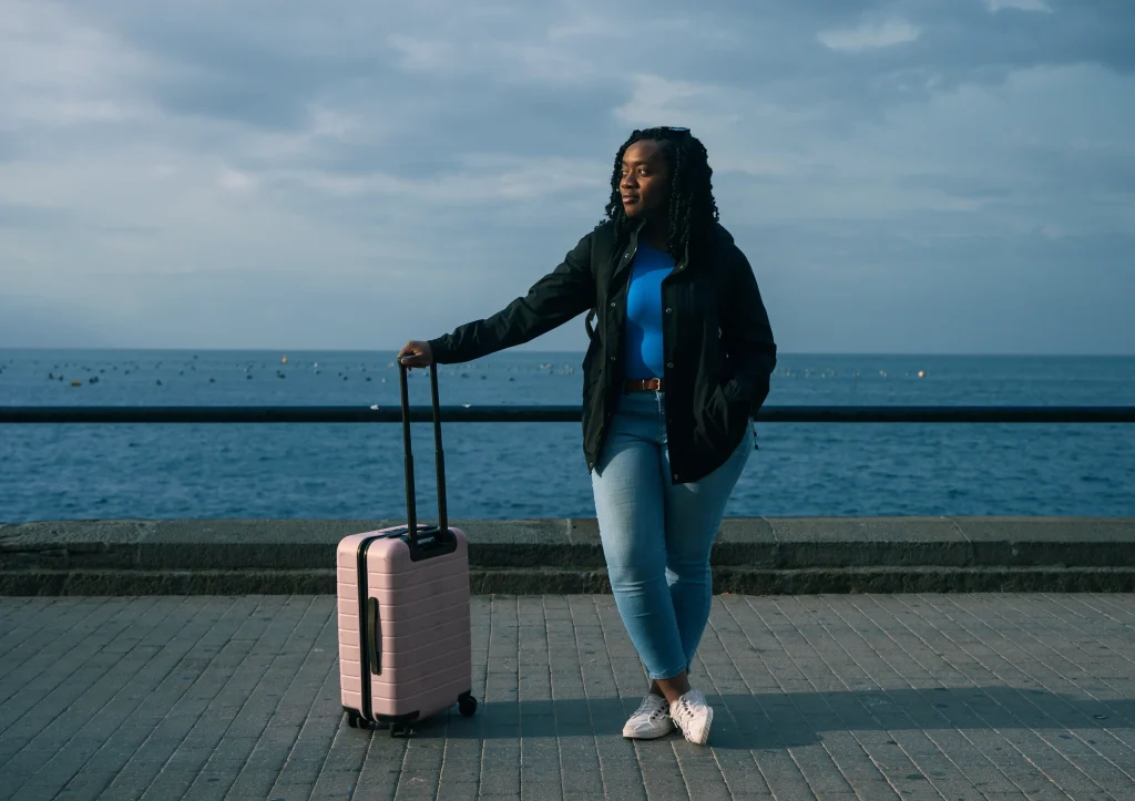 woman with travel suitcase standing by the ocean