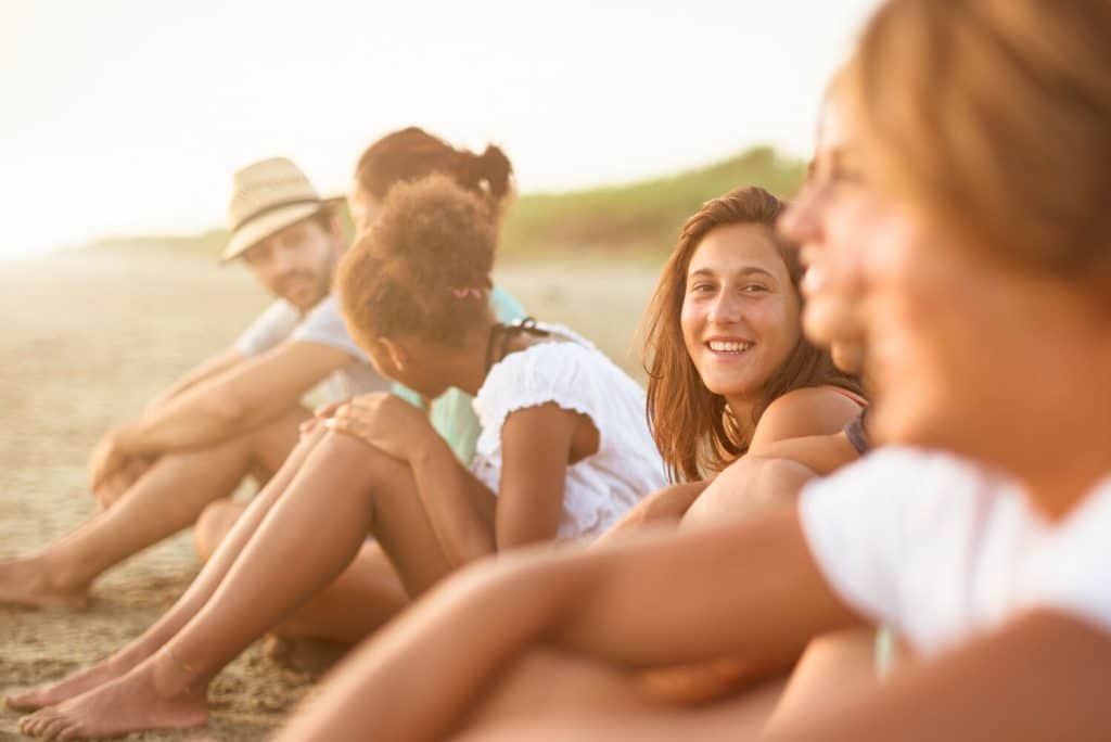 group of people sitting on a beach looking at the sea