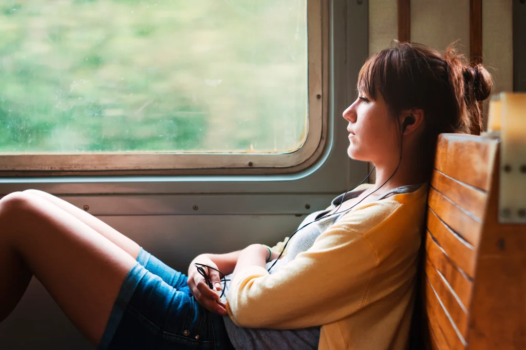 woman sitting in train listening to music