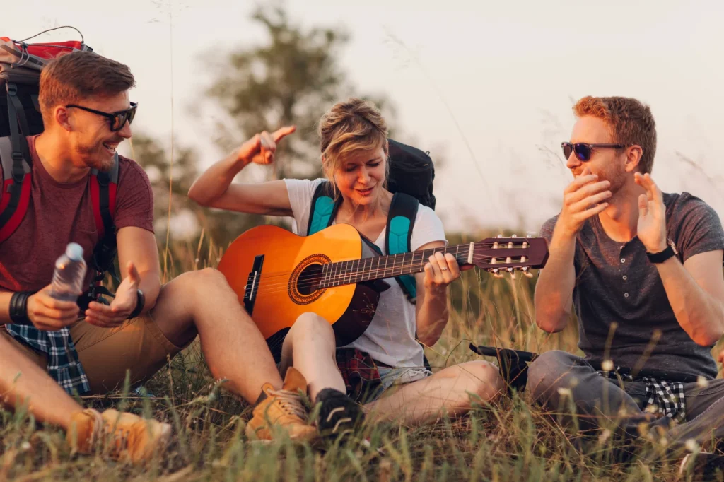 a woman playing guitar with two other people gathered around