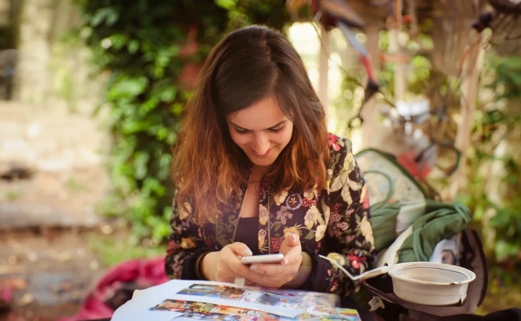 woman sitting at a table outside looking at her phone