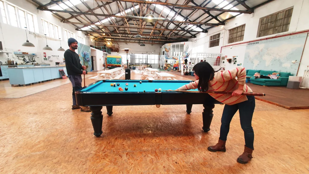 a communal area in a hostel with a billiard table where people are playing