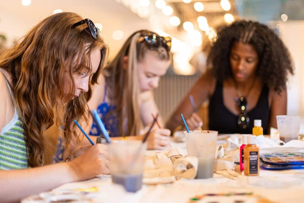 three women painting in a class in a hostel