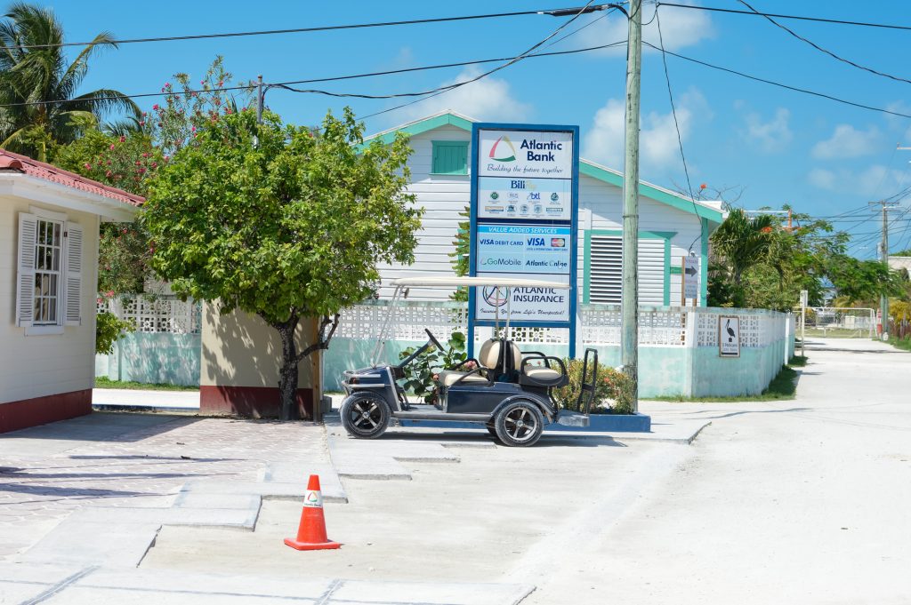 Tropical Caye Caulker island on a sunny day, Belize. Caye Caulker, Belize - March 24, 2015: Tropical island, all covered with white sand, with people and businesses is seen on a sunny day