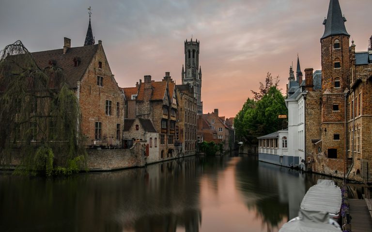 brown concrete buildings beside calm body of water in Bruges, day trips from brussels