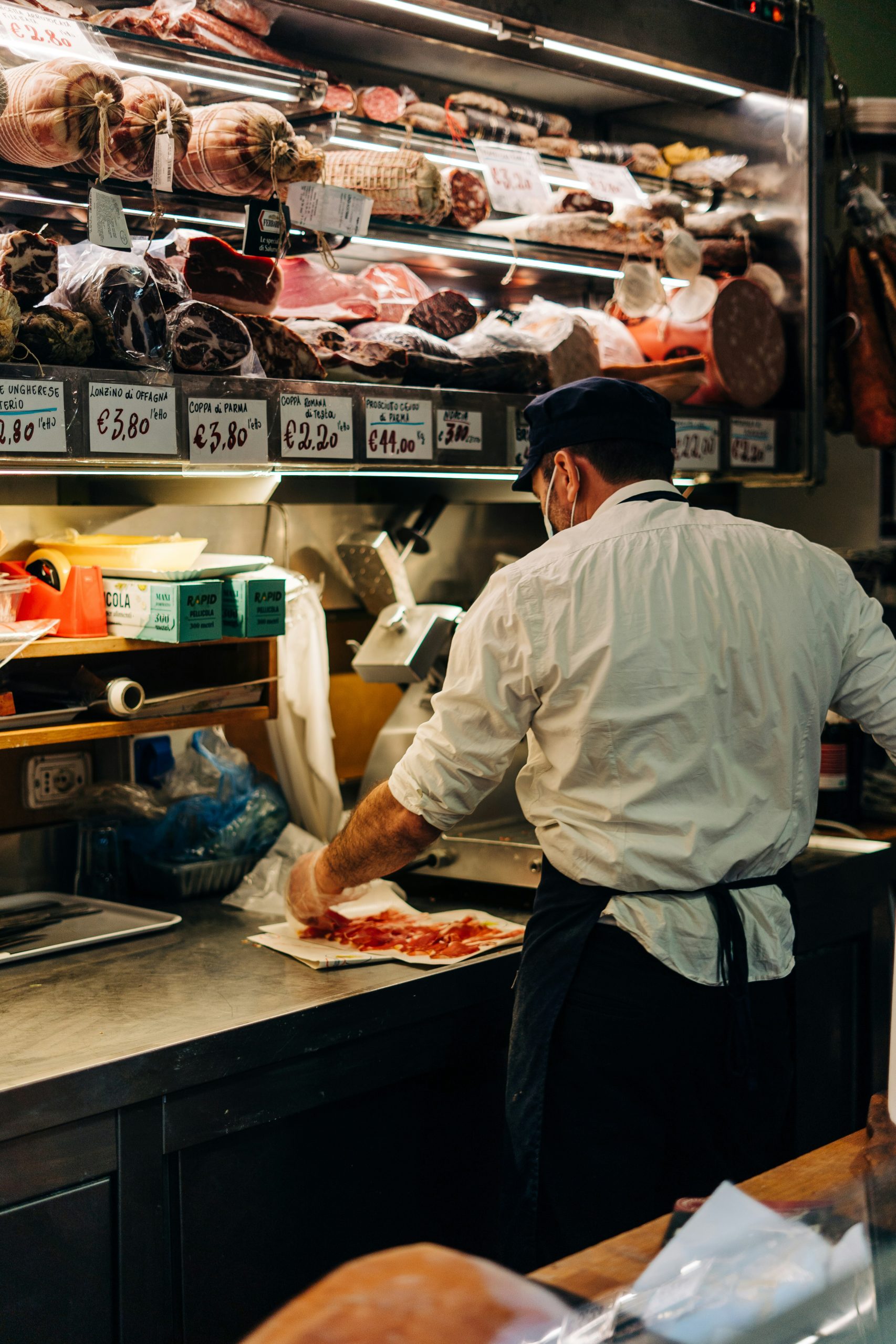 man cutting slices of curated meat