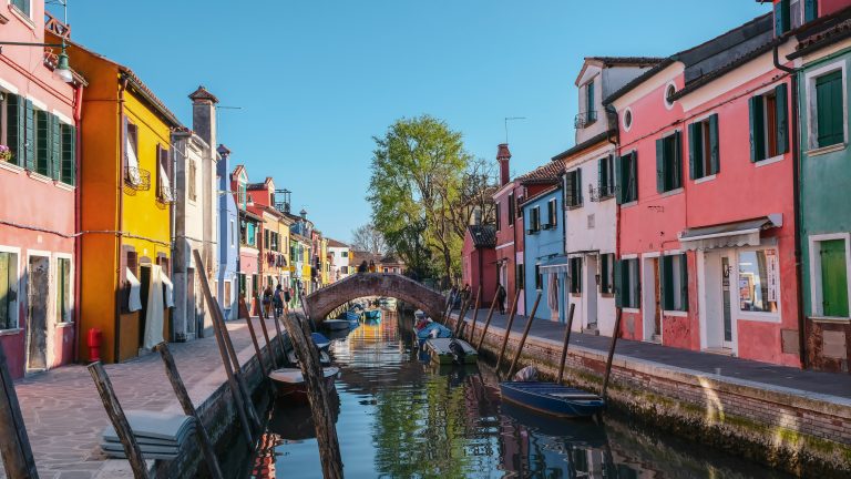boats on river between colorful houses, day trips from venice