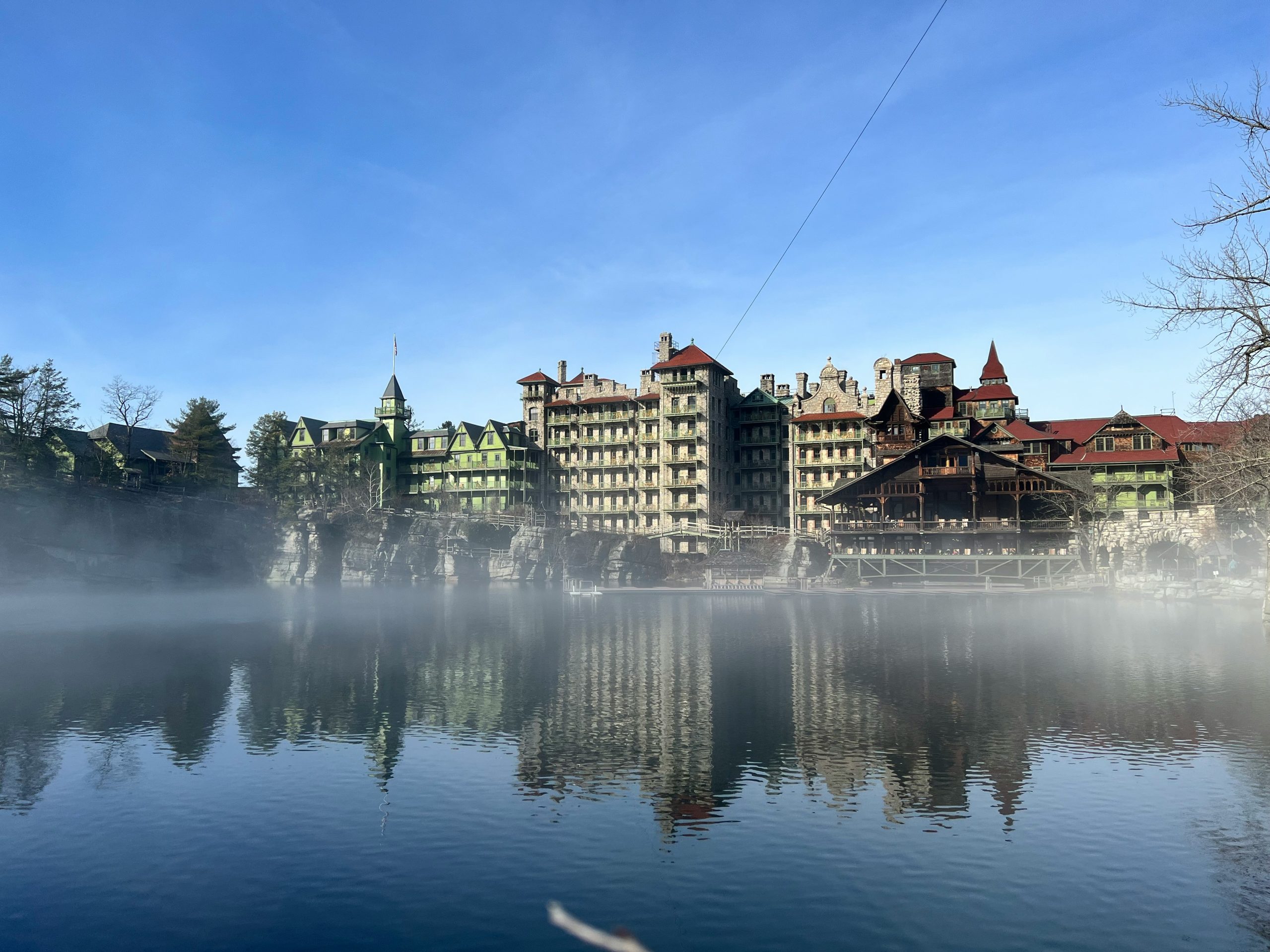 a large building sitting on top of a lake next to a forest