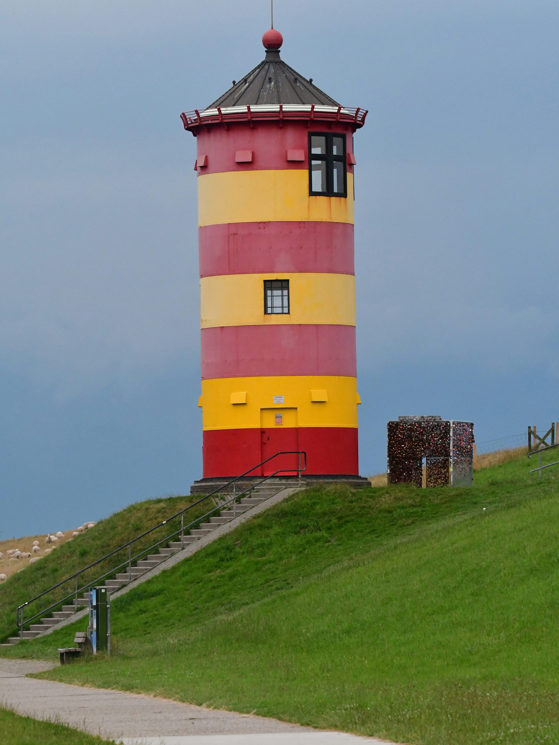 a colorful lighthouse stands tall in a grassy hill