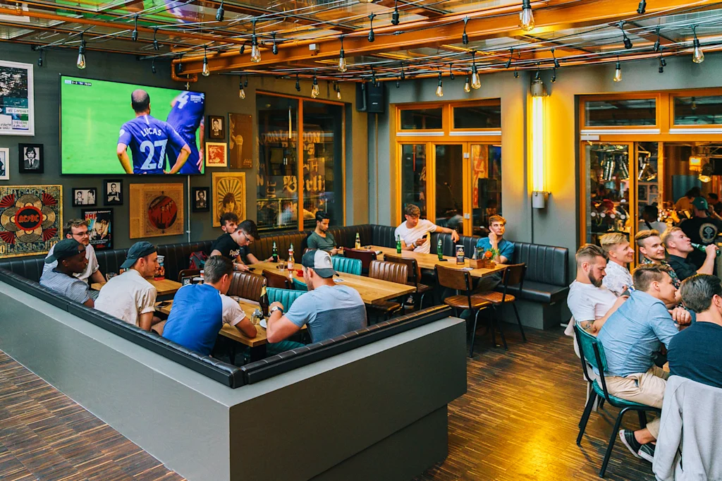 people watching a football game in a communal hostel area