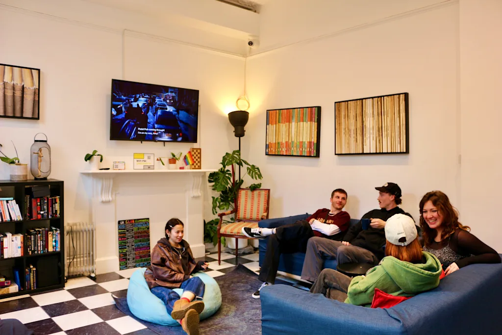people sitting watching tv and talking in a common room at a hostel