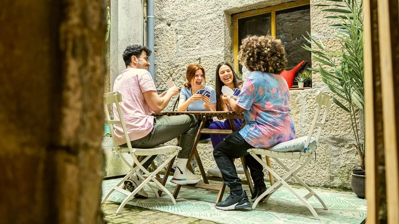Travellers sitting around a table in a hostel courtyard