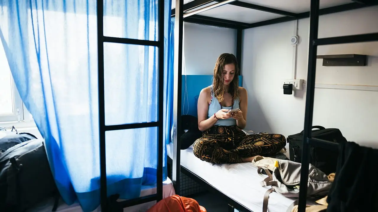 A solo traveller on a hostel bunk with her pack beside her