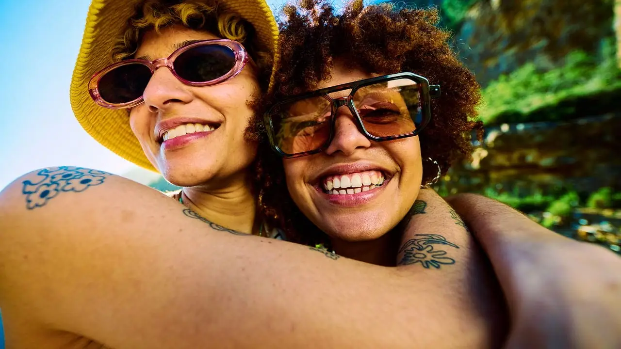 Two friends arm in arm, taking a photo together outdoors